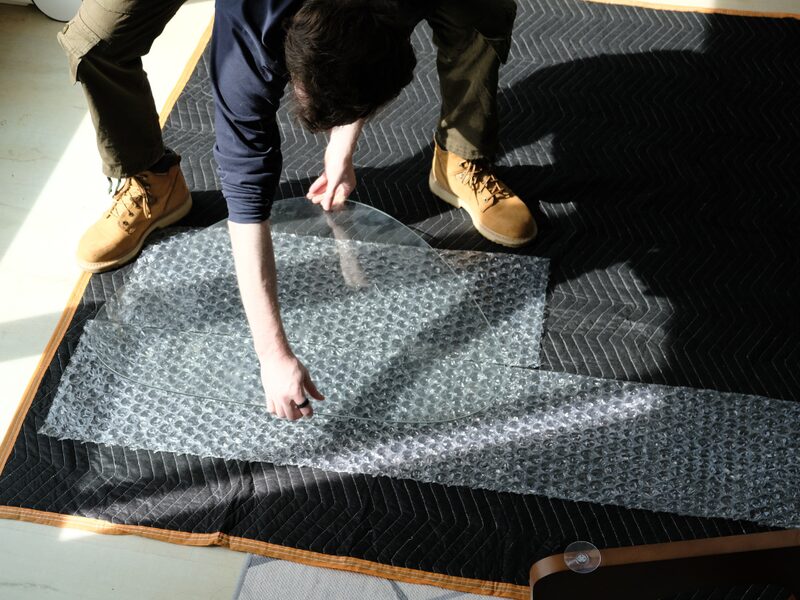 Glass tabletop being carefully wrapped in bubble wrap